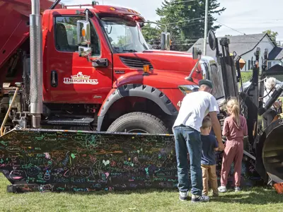 Children sign their names on the front of a snowplow.